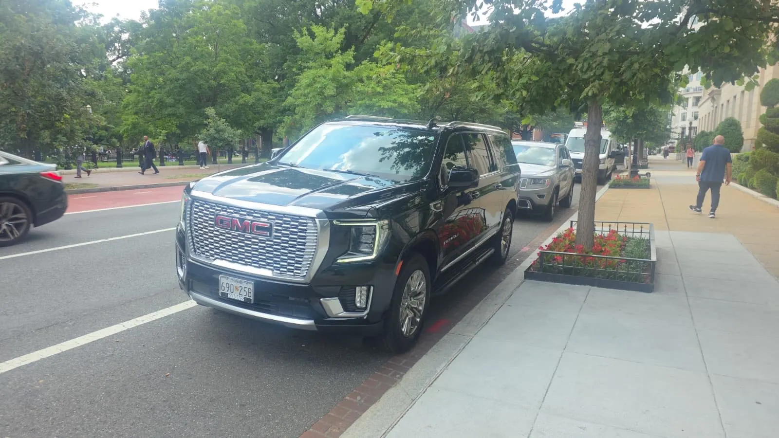 Black luxury SUV parked curbside on a tree-lined street in downtown Washington, DC